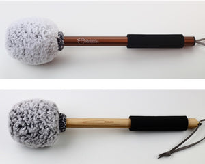 Fuzzbucket Gong mallets on two different handles.  Both mallets have a head wrapped in grey sherpa.  The top mallet has a bronze-colored aluminum handle and the bottom has a wooden handle.  Both have a black foam grip and strings for hanging.